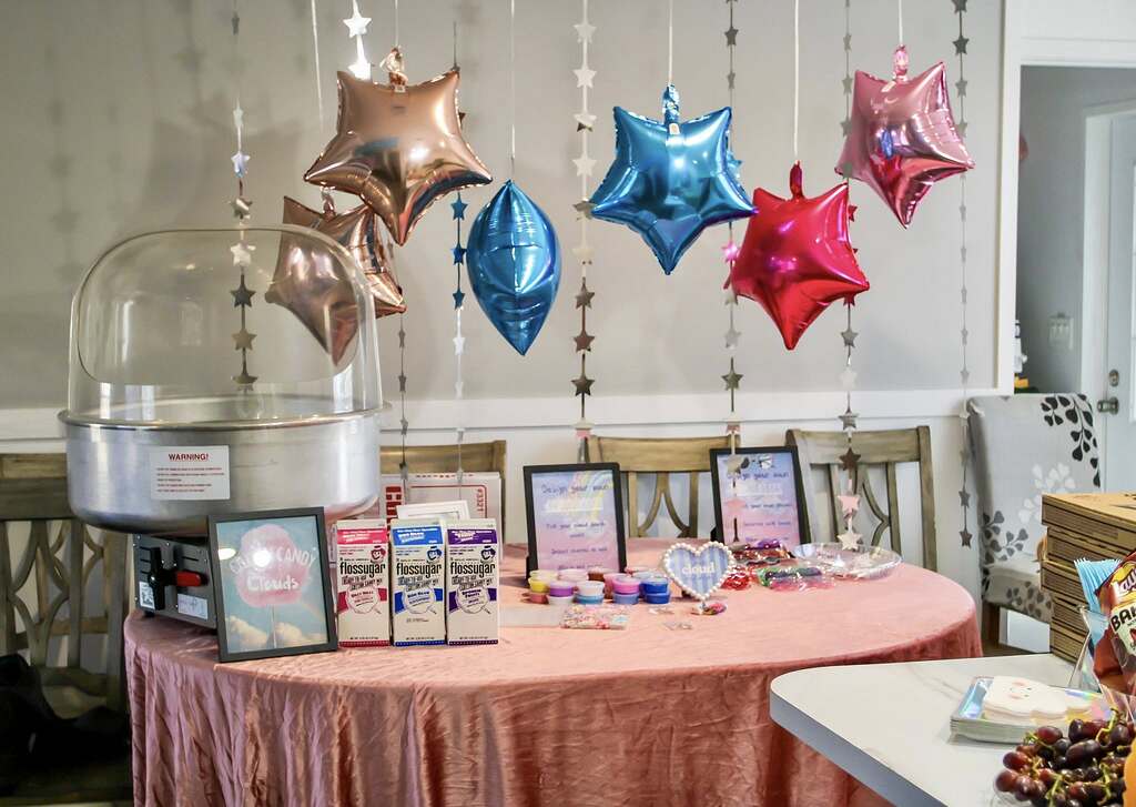 Table setup featuring a cotton candy machine, Flossugar cartons, and DIY project signage under floating star balloons
