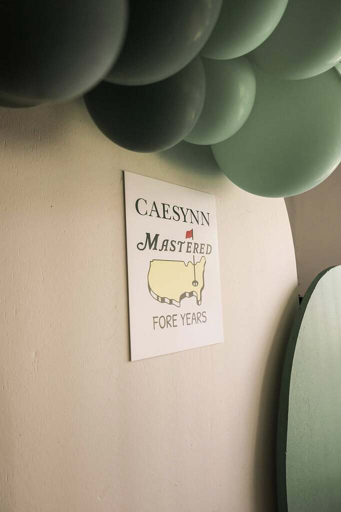 Golf themed birthday sign reading Caesynn Mastered Fore Years with balloons