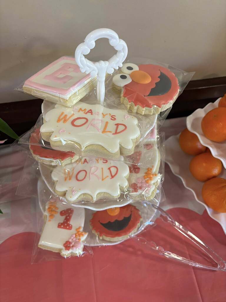 Tiered tray filled with individually wrapped sugar cookies featuring Elmo designs and text reading Emaay's World.