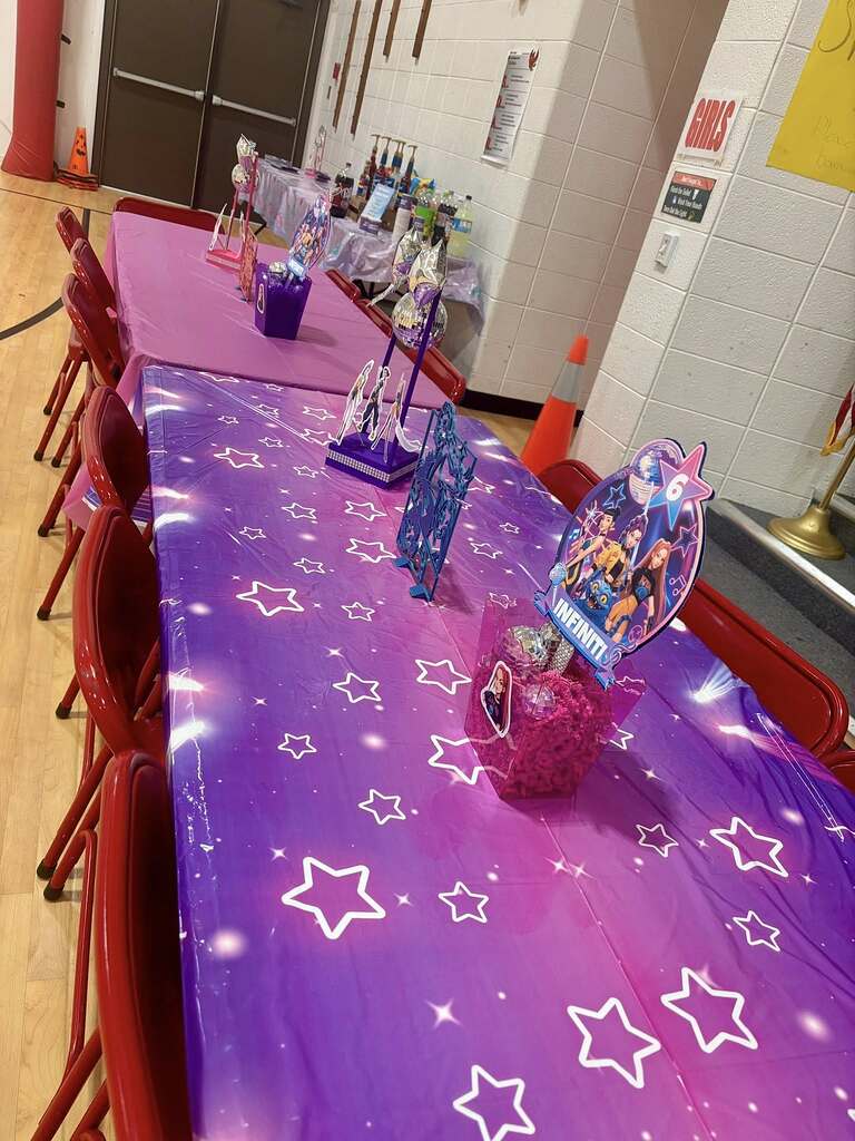 Purple and pink star-patterned tables set up for a themed party with character centerpieces.