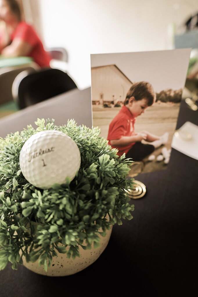 Golf ball tucked into a small green plant next to a framed photo of a young boy.