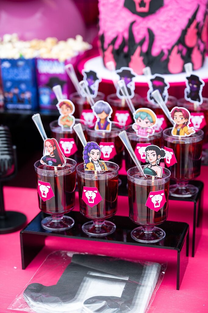 Drinks with anime character toppers served in clear cups at a themed party